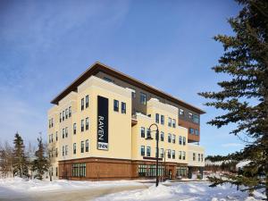 ホワイトホースにあるRaven Inn Whitehorseの雪面の看板が貼られた大きな建物