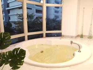 a large bath tub in a room with a window at Jacuzzi POOL 3Bedroom, walk to Stadium in Kuala Lumpur