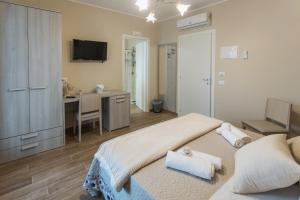 a bedroom with a bed and a desk and a television at Oasi Perla Del Mare Rooms in Aci Castello