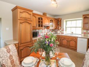 uma cozinha com uma mesa com um vaso de flores em Low Shipley Cottage em Cotherstone