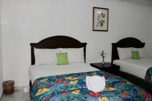 a bedroom with two beds with a hat on the bed at Hotel El Cid in Mérida