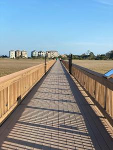 a wooden bridge over a field with buildings in the background at Steps away from the BEACH!!! in Hilton Head Island