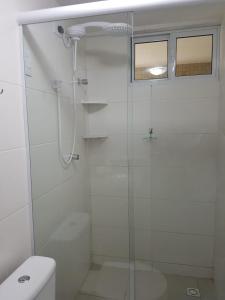 a white bathroom with a shower and a toilet at Flat 102 com vista parcial do Mar! in Cabedelo