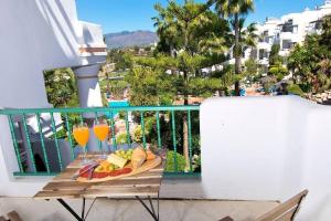 bandeja de comida en el balcón con vasos de zumo de naranja en Spectacular Apartment in Matchroom Country Club, en Fuengirola
