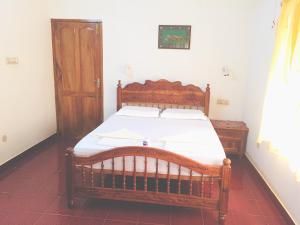 um quarto com uma cama de madeira e uma porta de madeira em Ganesh House Ayurveda Homestay em Kovalam