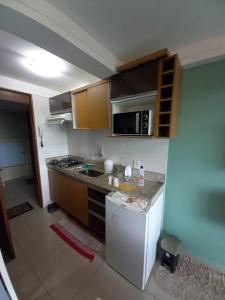 a kitchen with a white refrigerator and a microwave at Flat 102 com vista parcial do Mar! in Cabedelo