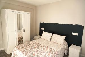 Schlafzimmer mit einem Bett mit einem schwarzen Kopfteil in der Unterkunft alojamiento dos de mayo in Gijón