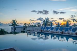 a pool with chairs and a sunset in the background at La Vista Resort in Simpson Bay