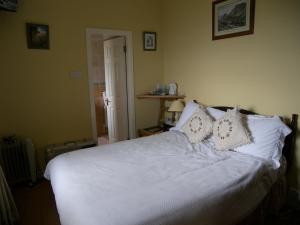 1 dormitorio con 1 cama con sábanas y almohadas blancas en Achill View B&B, en Murrisk