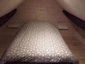 a large bed in a attic with a wooden floor at La Cahute, gîte étape in La Forêt-Auvray