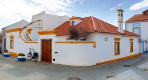 a white house with a red roof and a bike parked outside at Casa Ocre in Vila Nova de Milfontes