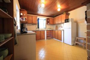 a kitchen with a white refrigerator and wooden cabinets at Casa Ocre in Vila Nova de Milfontes