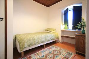 a bedroom with a bed and a window and a rug at Casa Ocre in Vila Nova de Milfontes