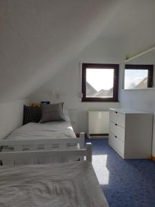 sypialnia z łóżkiem, komodą i oknem w obiekcie Ferienhaus "Hygge Friedrichskoog-Spitze" w mieście Friedrichskoog