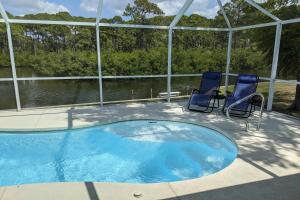 a patio with two chairs and a swimming pool at Mangrove View on Oyster Creek in Englewood