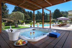 een zwembad met een hot tub op een houten terras bij Bella Foresta Villa in Ialyssos
