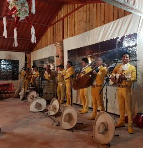 um grupo de homens em pé em um palco com instrumentos em Hotel Posada Rancho Los Laureles 