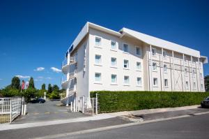 un bâtiment blanc sur le côté d'une rue dans l'établissement ibis budget Bordeaux Sud, à Villenave-dʼOrnon