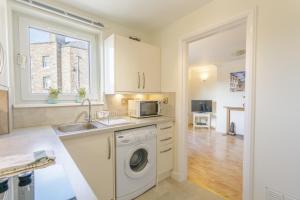 eine Küche mit einer Waschmaschine und einem Waschbecken in der Unterkunft Pleasance Apartment in Edinburgh