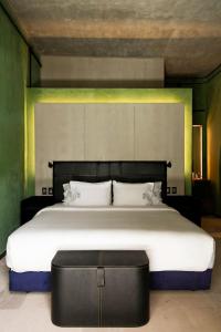 瓦哈卡德華雷斯的住宿－Pug Seal Oaxaca，一间卧室配有一张大床和一张黑色的搁脚凳