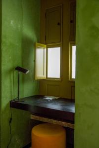 a green room with a stool and two windows at Pug Seal Oaxaca in Oaxaca City