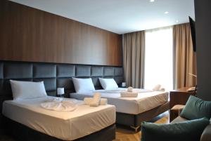 een hotelkamer met 2 bedden en een bank bij Twin Towers Hotel City & Beach Resort in Shëngjin