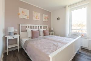 a white bedroom with a bed and a window at Luftkurort - 5 Sterne Ferienhaus - See-Kamin-Sauna-Garten in Krakow am See