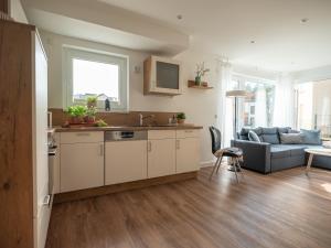 a kitchen with a sink and a living room with a couch at Luftkurort - 5 Sterne Ferienhaus - See-Kamin-Sauna-Garten in Krakow am See