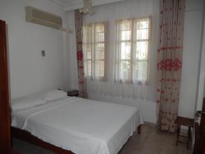 a bedroom with a white bed and two windows at Villa Truva in Fethiye