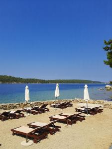 een groep ligstoelen en parasols op een strand bij Apartments Štokić in Rab