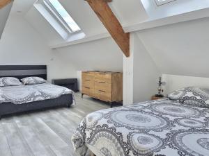 Un dormitorio con dos camas y suelo de madera. en En toute simplicité, en Lavilletertre 17 fotos más