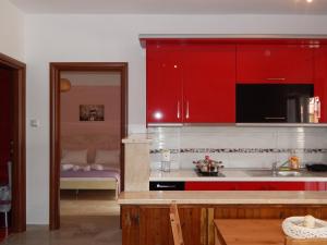 eine Küche mit roten Schränken und einem Waschbecken in der Unterkunft Palm House Nikiti - Apartments Vicky in Nikiti