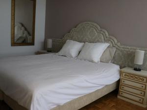 a bedroom with a large white bed and a nightstand at Belvilla by OYO Casa Alegr a in Galapagar