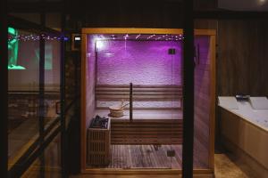 une porte ouverte sur une salle de bains avec éclairage violet dans l'établissement Capsule Gaming balnéo & billard & babyfoot & sauna 2 chambres, à Valenciennes