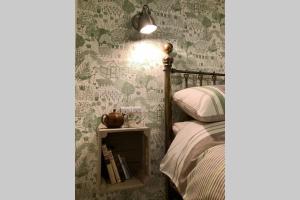 um quarto com papel de parede verde e branco e uma cama em Melford Allotment Shed-Vintage Lodge Suffolk em Long Melford