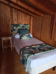 a bed in a room with a wooden wall at Casa Rural La Cabaña in Cangas de Onís