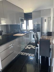 eine Küche mit Küchengeräten aus Edelstahl und einem Tisch mit Stühlen in der Unterkunft Appartement à Esmoriz de 3 pièces - 72m2 in Esmoriz