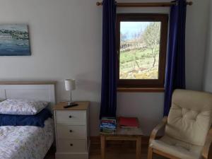 a bedroom with a bed and a chair and a window at Croft No.8 Bed & Breakfast in Ullapool