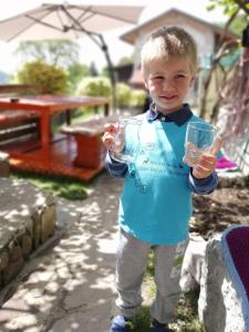 Młody chłopiec trzymający szklankę na podwórku w obiekcie Jelenov breg pod Matajurem w mieście Kobarid