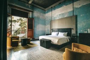 a bedroom with a bed and two chairs in it at Pug Seal Oaxaca in Oaxaca City