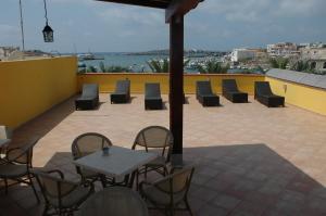 a patio with chairs and tables on a roof at Puesta De Sol Residence in Lampedusa