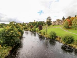 a river flowing through a park with trees and houses at Foxglove Cottage in Richmond