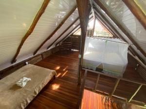 an attic room with a bed and a window at Eco Guest House- Sarapiquí 2 in Sarapiquí
