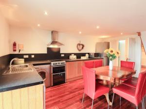 a kitchen with a wooden table and red chairs at Vista Cottage in Dalbeattie