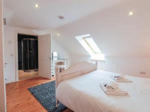 a white bedroom with a bed with towels on it at Vista Cottage in Dalbeattie