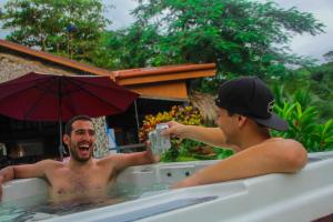 two men laughing in a bath tub with an umbrella at Hotel Poza Blanca Lodge in San Mateo