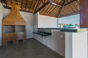 a kitchen with a brick fireplace and a sink at Carneiros Paradise - Casa de Luxo em Condomínio in Tamandaré
