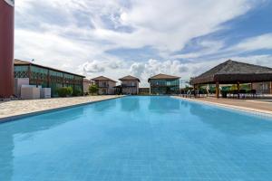 a large blue swimming pool in front of a building at Carneiros Paradise - Casa de Luxo em Condomínio in Tamandaré