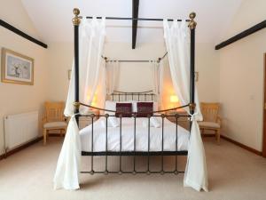 a bedroom with a four poster bed with curtains at Beechwood in Wood Norton