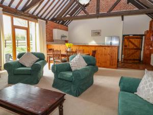 a living room with two green chairs and a table at Pear Tree in Wood Norton